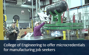 Two people in baseball caps and safety glasses work in a manufacturing plant